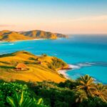 Sumba island landscape with hills, ocean, and huts.